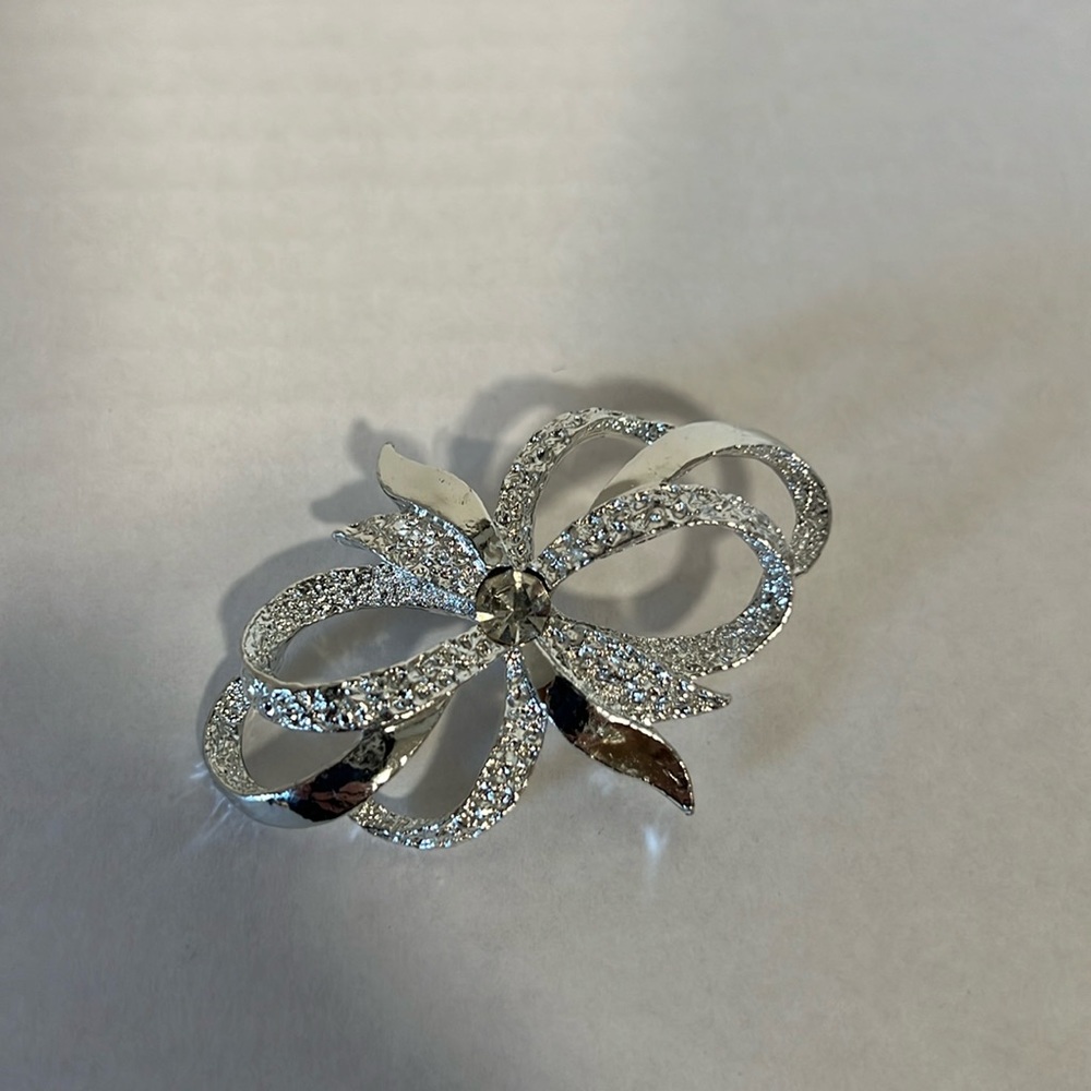 Beautiful silver tone brooch to look like a bow with crystal center